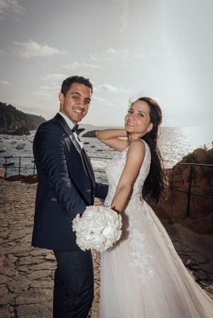 Postboda. Recién casados en el amanecer, vestidos de novios en la playa. Cola de vestido de novia. Costa brava España.